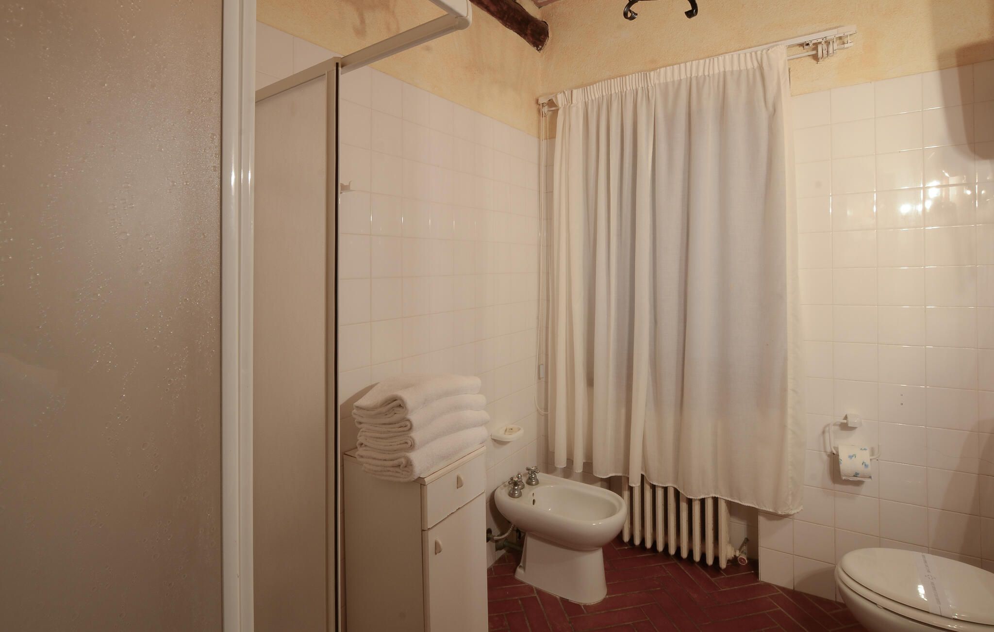 Un baño con ducha, un bidé, un inodoro y un perchero para toallas.