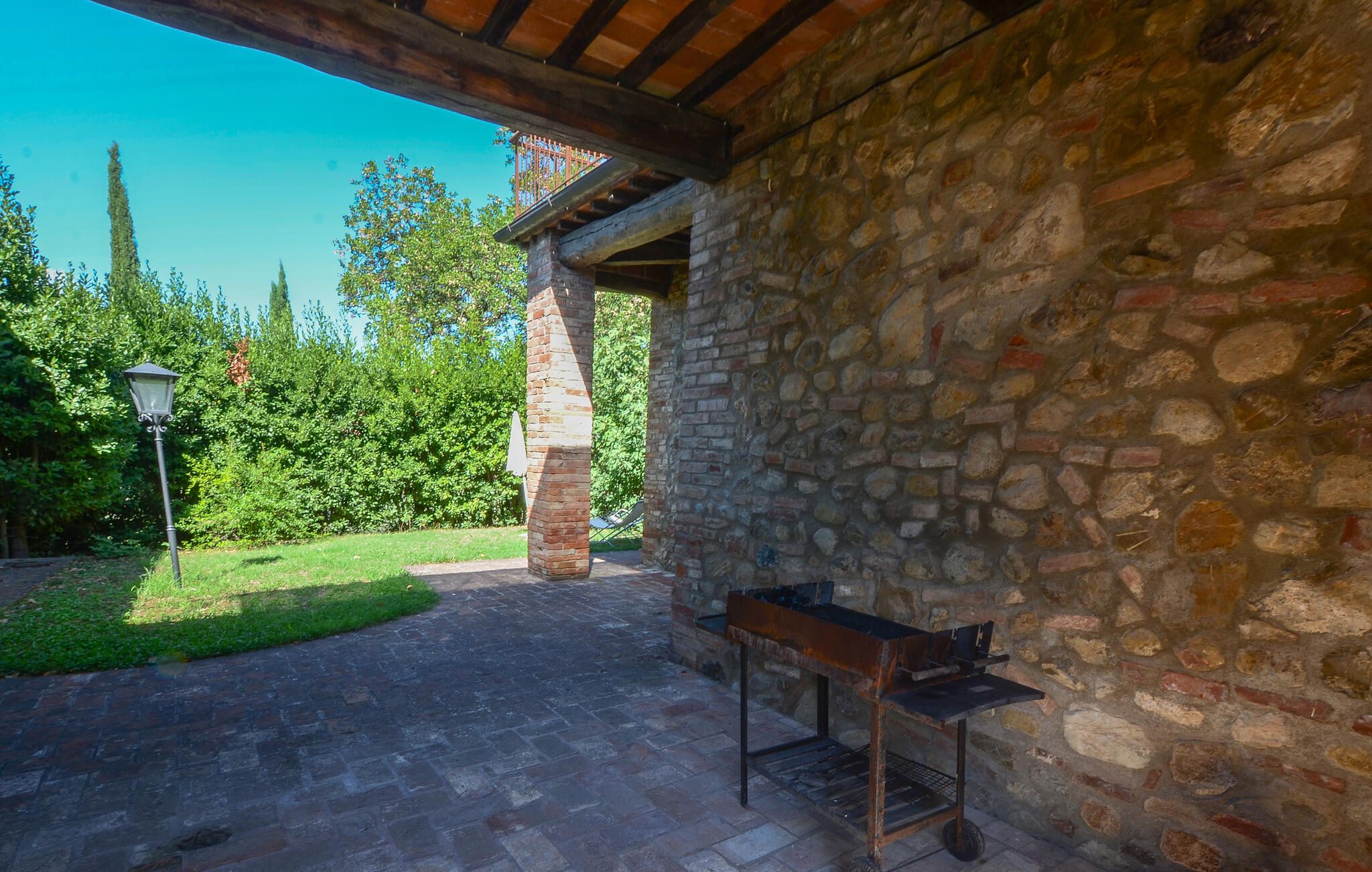 A stone building with a covered patio area, a metal bench, and a street lamp.