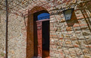 Ein Steinhaus mit roter Tür und einem Metallgitter.