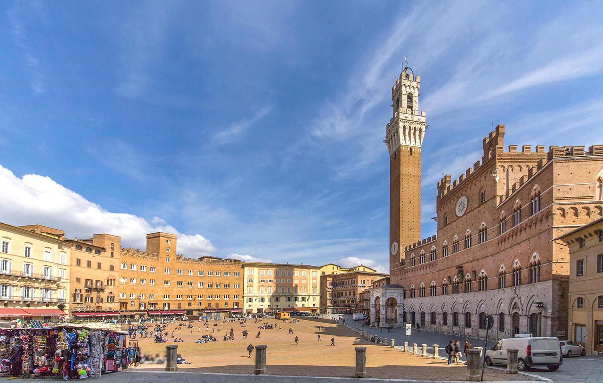 A spacious square with a prominent tower and historic buildings.
