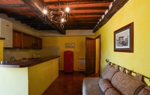 A compact kitchen with wooden cabinets, a red refrigerator, and a hanging light fixture. - Beautiful home in Murlo with outdoor swimming pool (Murlo)