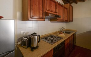 A kitchen with wooden cabinets, a gas stove, a toaster, and a kettle. - Gorgeous apartment in Murlo with WiFi (Murlo)