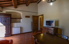 A room with a wooden table, a television, a door with a number, and a radiator. - Gorgeous apartment in Murlo with WiFi (Murlo)