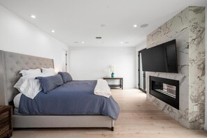 A modern bedroom with a bed, a TV, and a fireplace. - Penmar Meridian (Venice)
