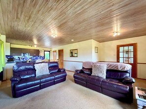 A spacious living area with two leather sofas, a wooden ceiling, and a view into the kitchen. - Hardy Chalet - UK47157 (West Stour, near Gillingham)