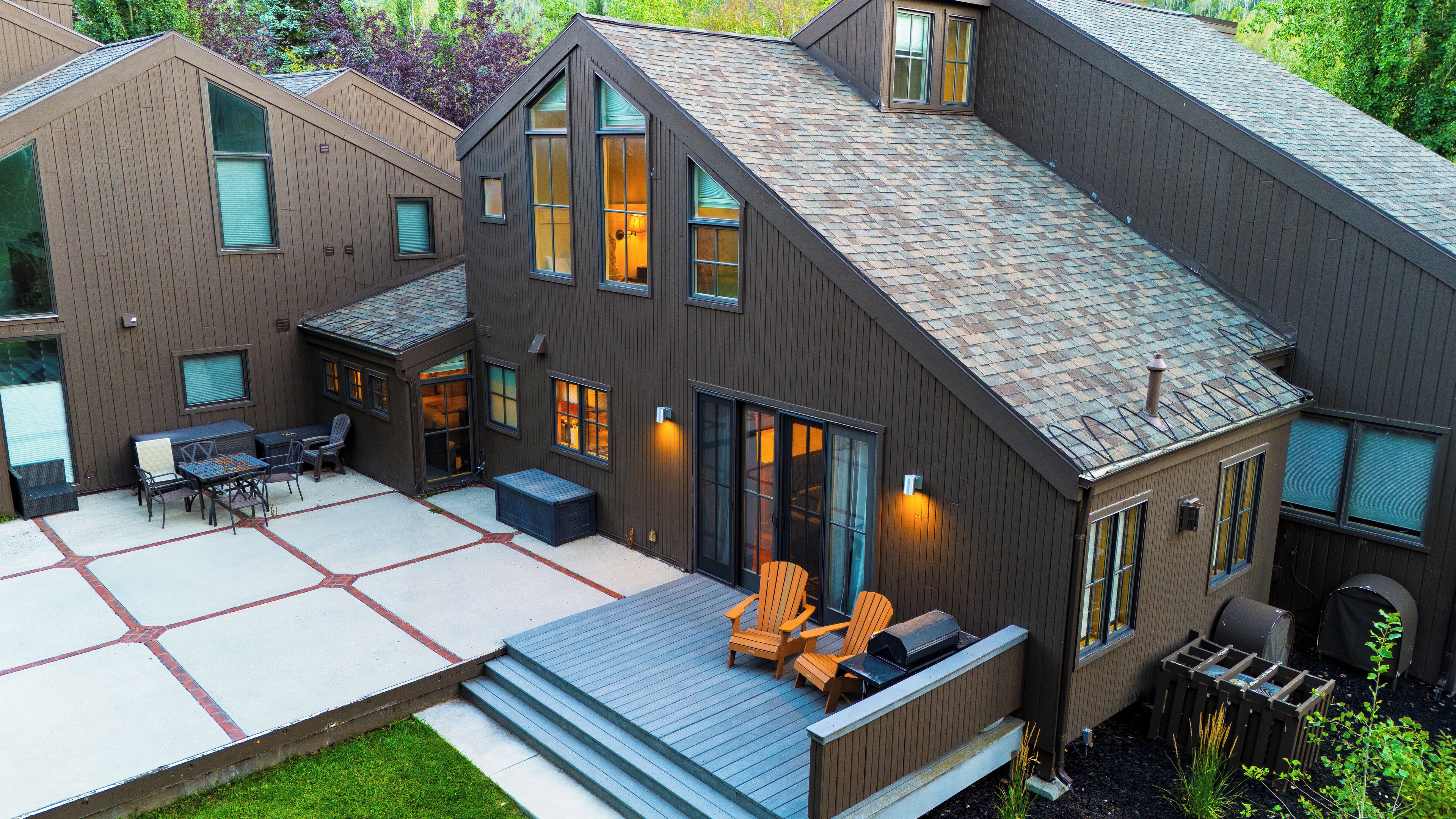 A modern house with a patio, outdoor seating, and a covered area.