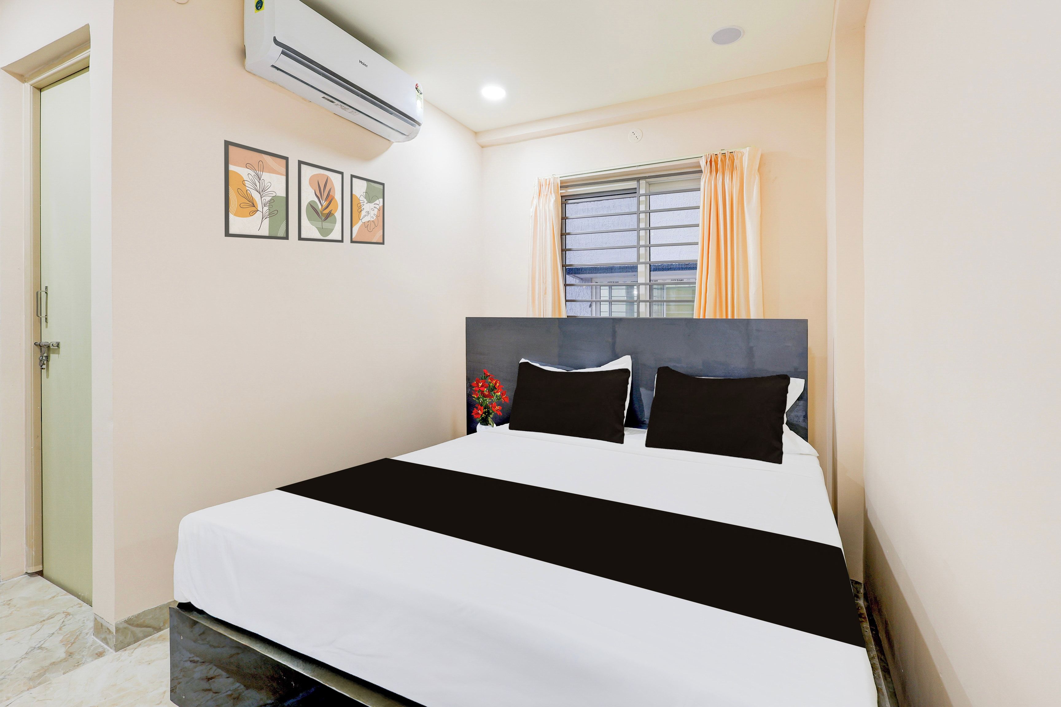 Quarto de hotel com cama, ar condicionado, janela com cortinas e porta.