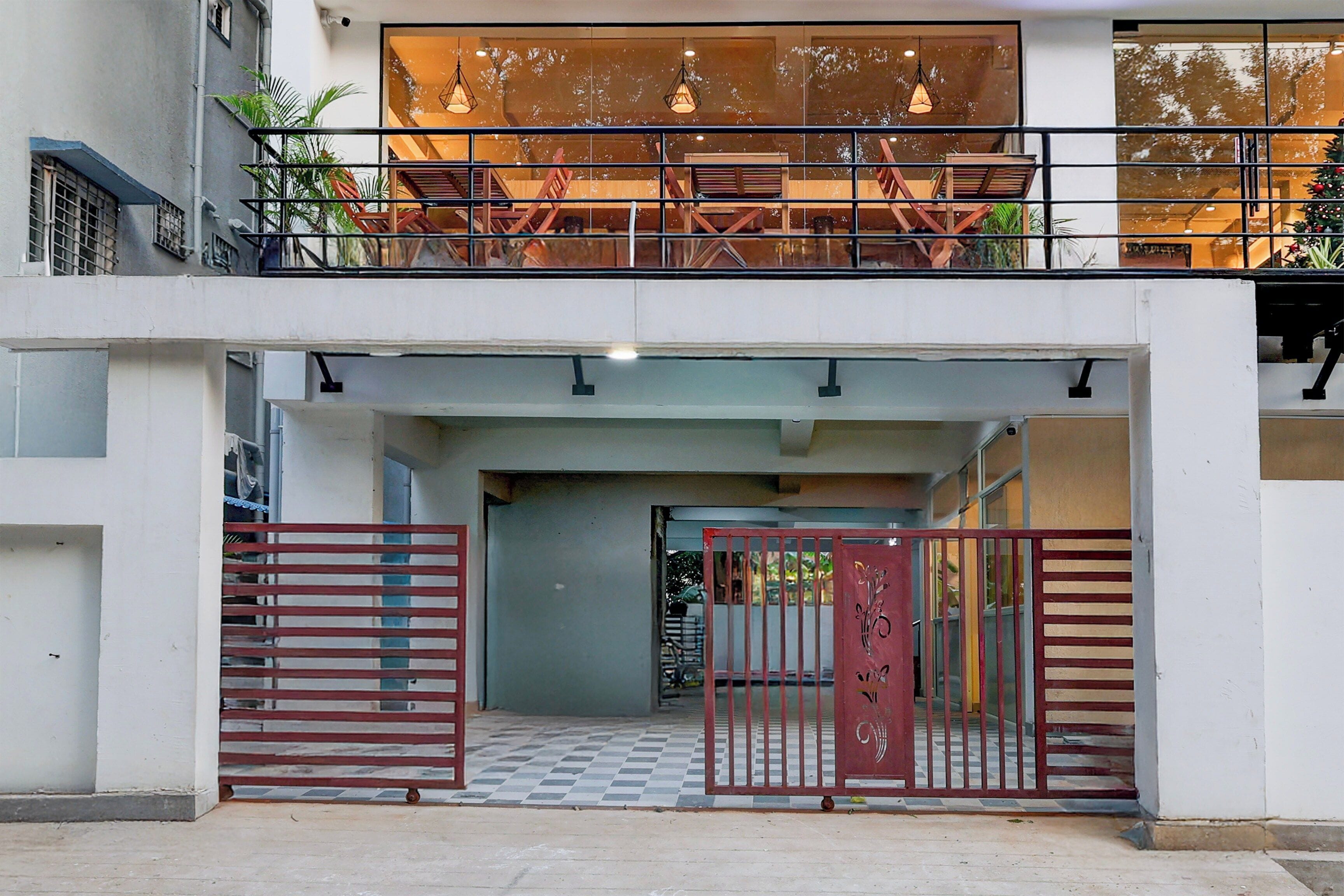 Entrada de un edificio con un camino de acceso con portón, piso a cuadros y un balcón con barandillas.