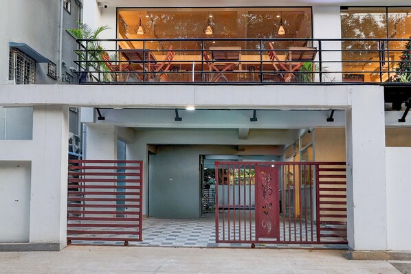 Une entrée d’immeuble avec une allée bordée de portails, un sol à carreaux et un balcon doté de balustrades.