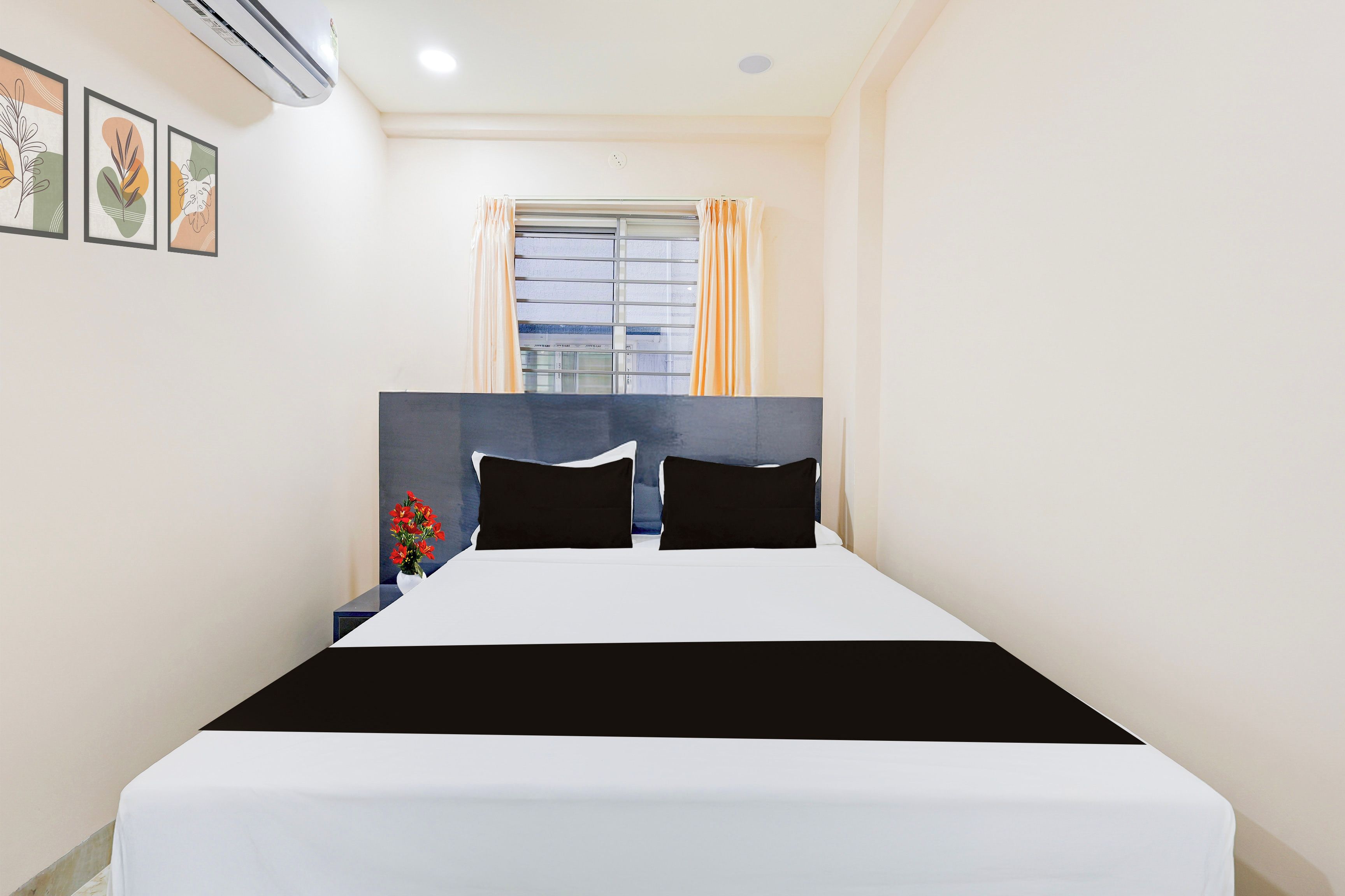 Une chambre d’hôtel avec un lit, une table de chevet, une fenêtre avec des rideaux et des œuvres d’art murales.