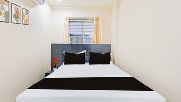 Une chambre d’hôtel avec un lit, une table de chevet, une fenêtre avec des rideaux et des œuvres d’art murales.