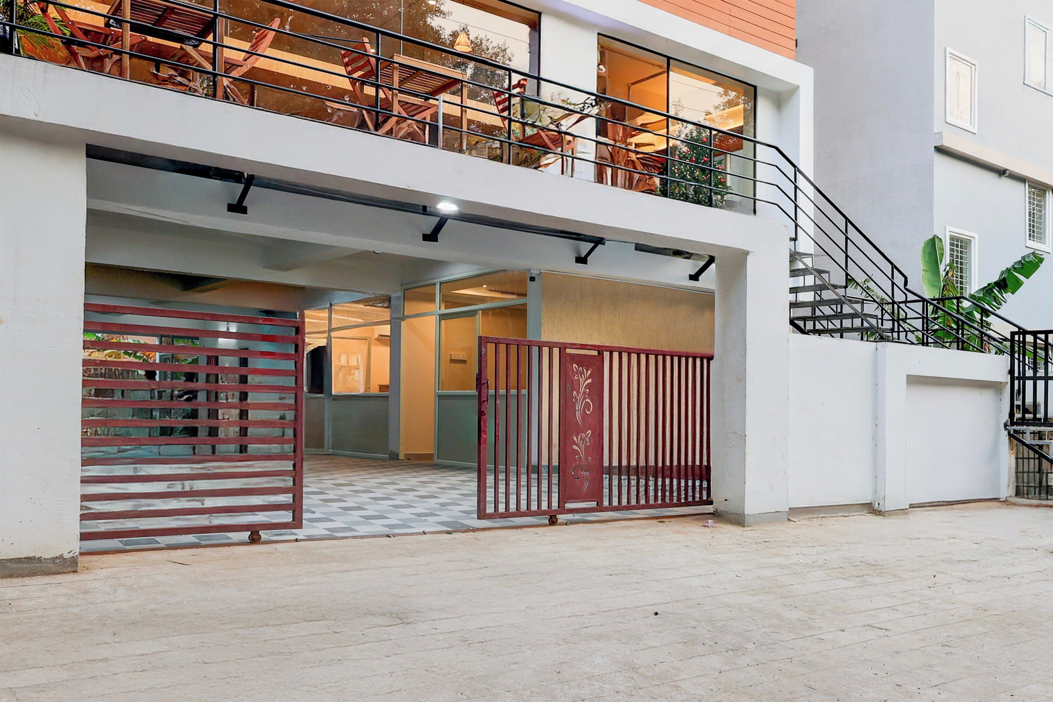 A modern building with a gated entrance, a balcony with railings, and a staircase leading to an upper level.