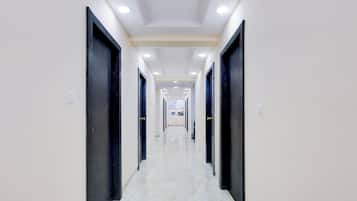 A corridor with doors on both sides, recessed lighting, and a marble floor.