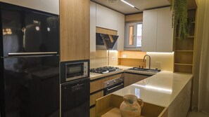 Eine moderne Küche mit einem schwarzen Kühlschrank, einem Einbauofen, einem Gasherd und einer Spüle.