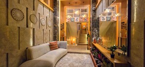 A modern interior with a sofa, decorative wall panels, a staircase, and a mirror reflecting the room. - Luxury 3BR Apartment with AC Elegant Area in 6th October (First 6thof october city)