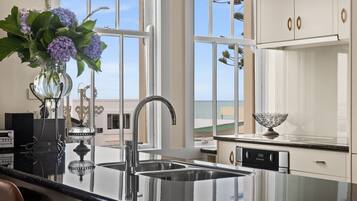 A modern kitchen with a large window, stainless steel appliances, and a vase with flowers on the counter.
