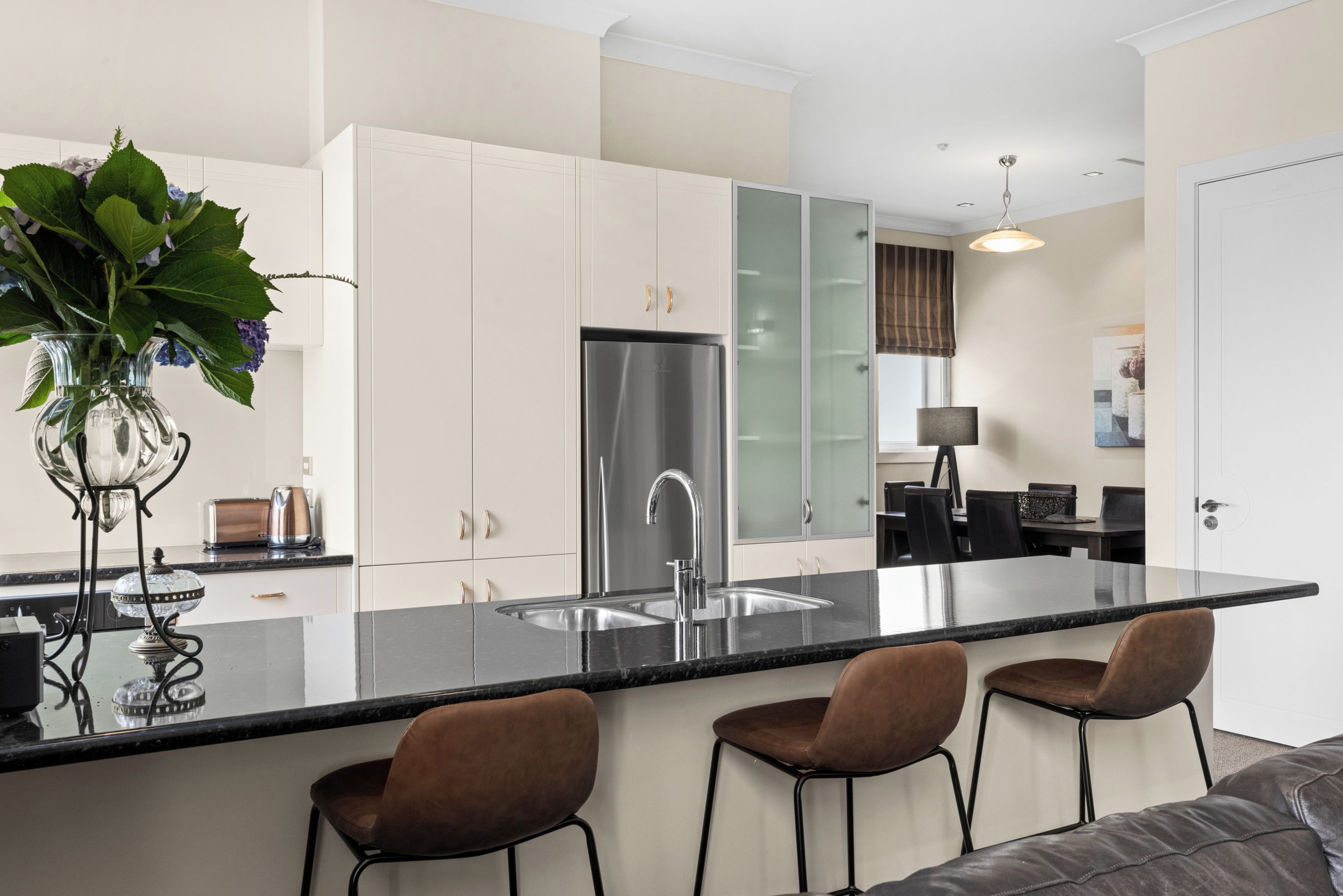 A modern kitchen with a central island, stainless steel appliances, and a seating area with bar stools.