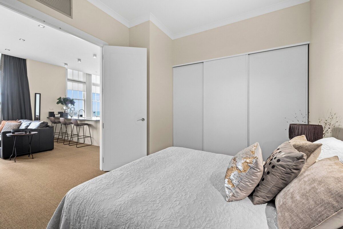 A hotel room with a bed, a seating area with a sofa and chairs, a desk, and a wardrobe.