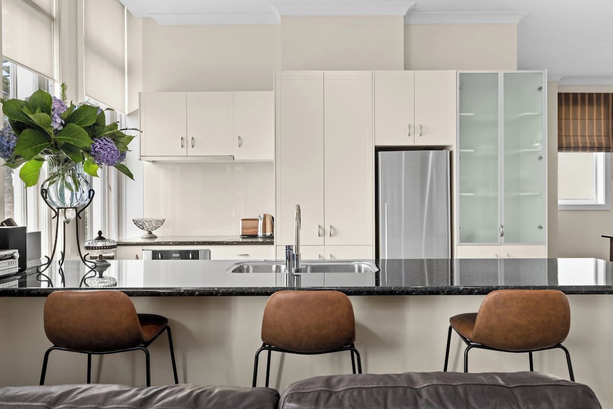 A modern kitchen with a central island, white cabinetry, and a stainless steel refrigerator.