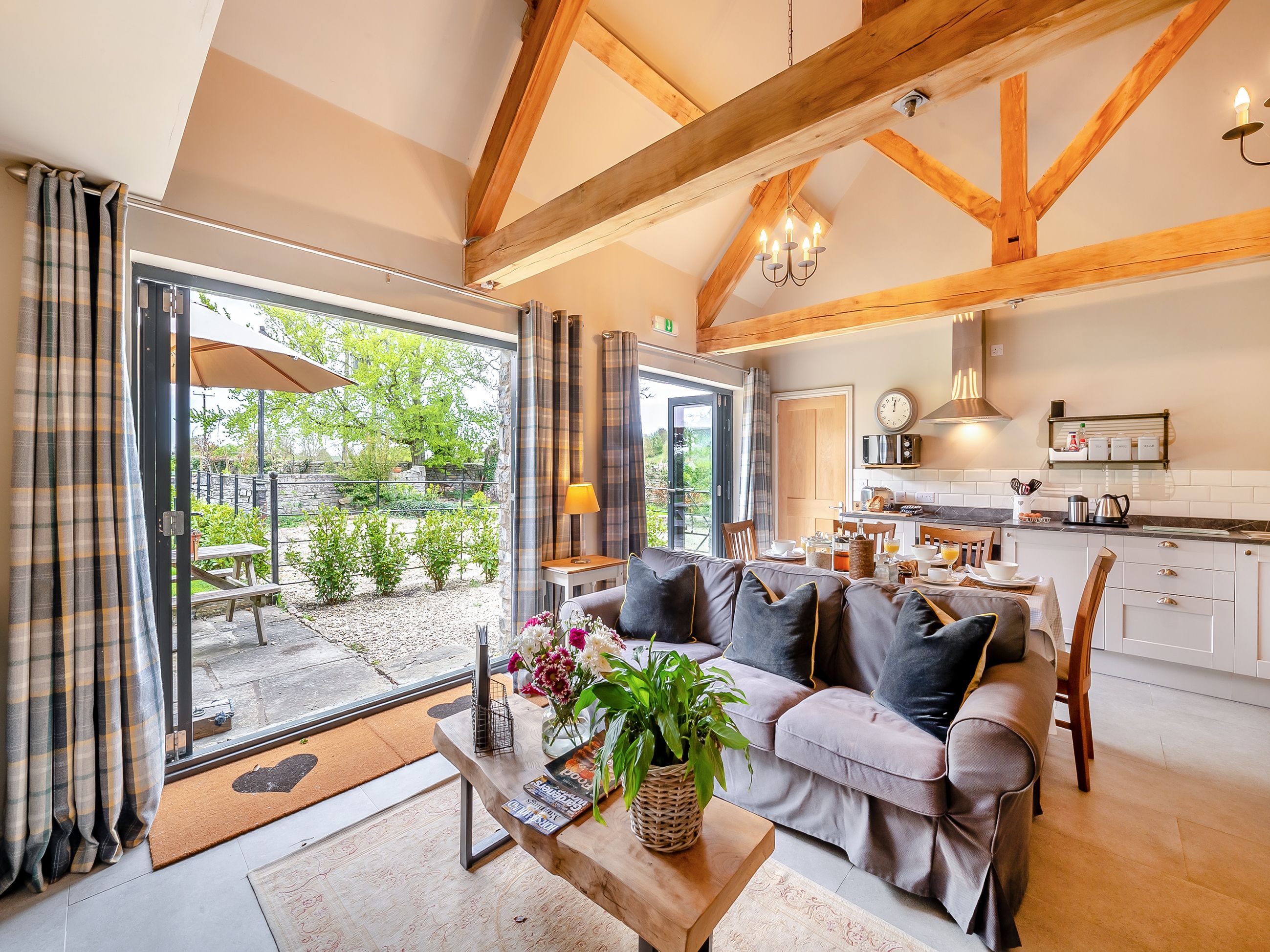 A cozy living room with a sofa, coffee table, and a view of the garden through large sliding doors.