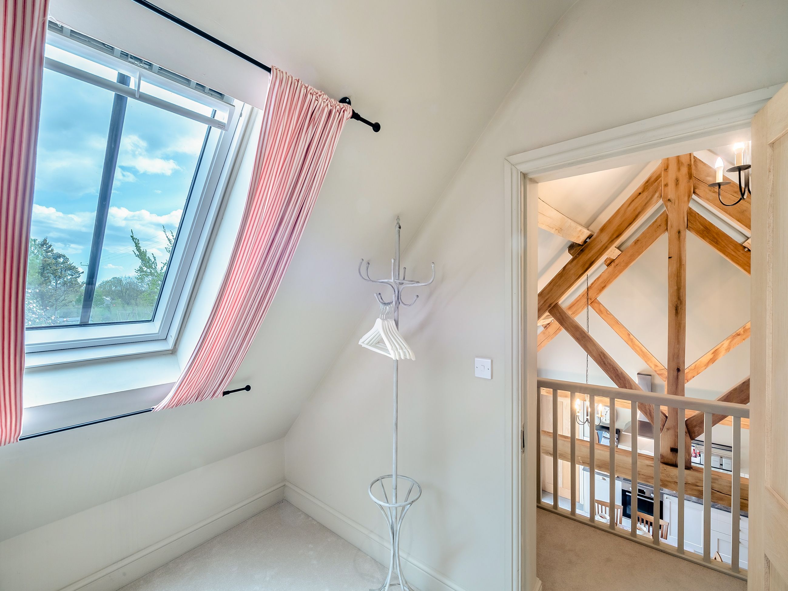 A room with a skylight, a floor lamp, and a view of a wooden staircase.