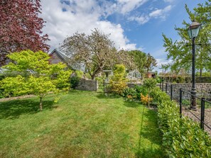 A well-maintained garden with a variety of trees and shrubs, a stone wall, and a metal fence. - 2 bedroom accommodation in Knole, near Langport (Knole, near Langport)