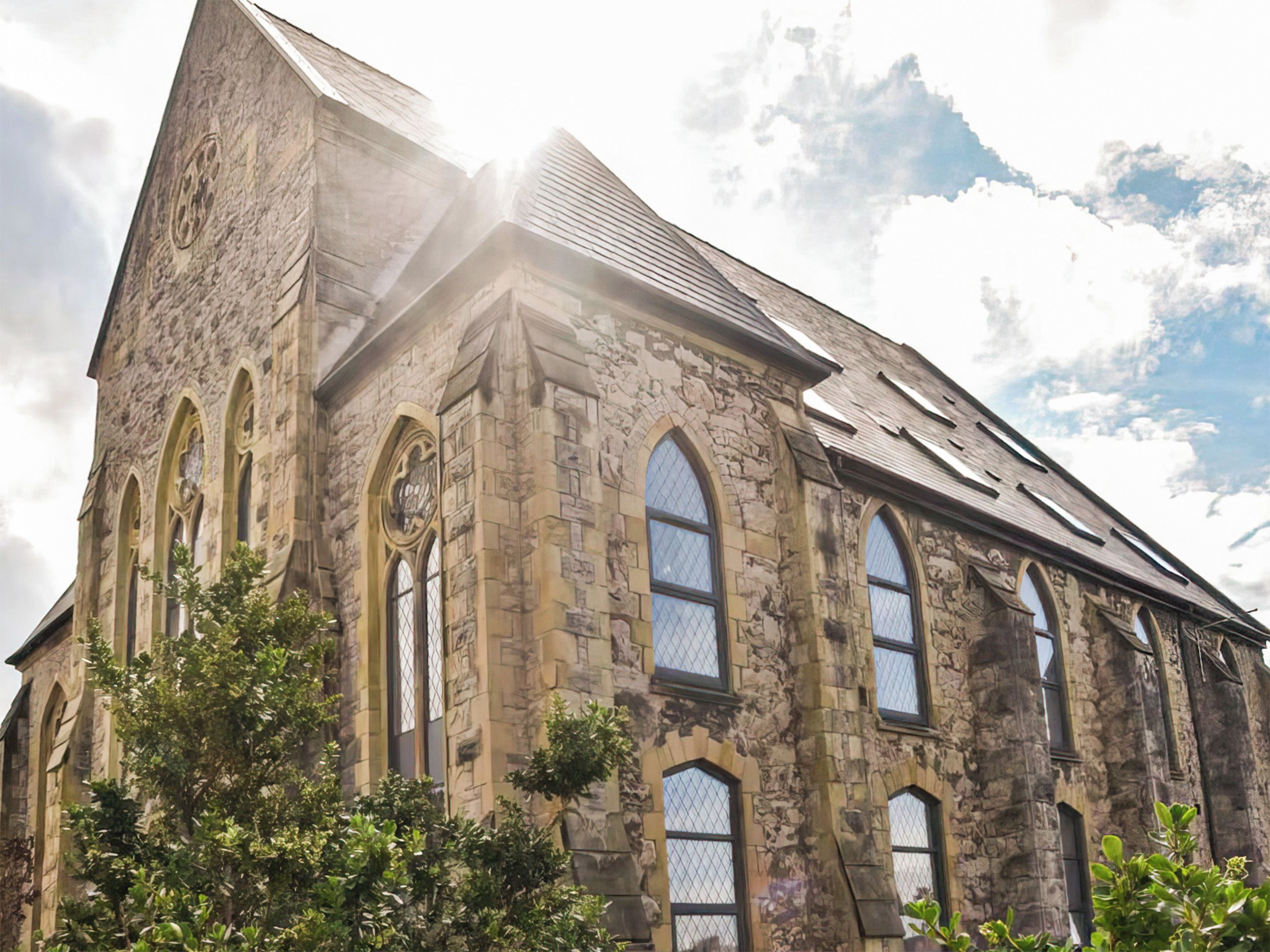 A historic stone building with arched windows and a steeply pitched roof.