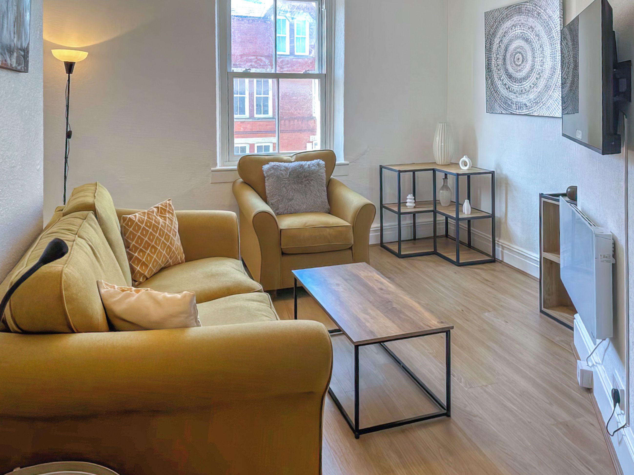 A living room with a sofa, armchair, coffee table, and a side table with decorative items.