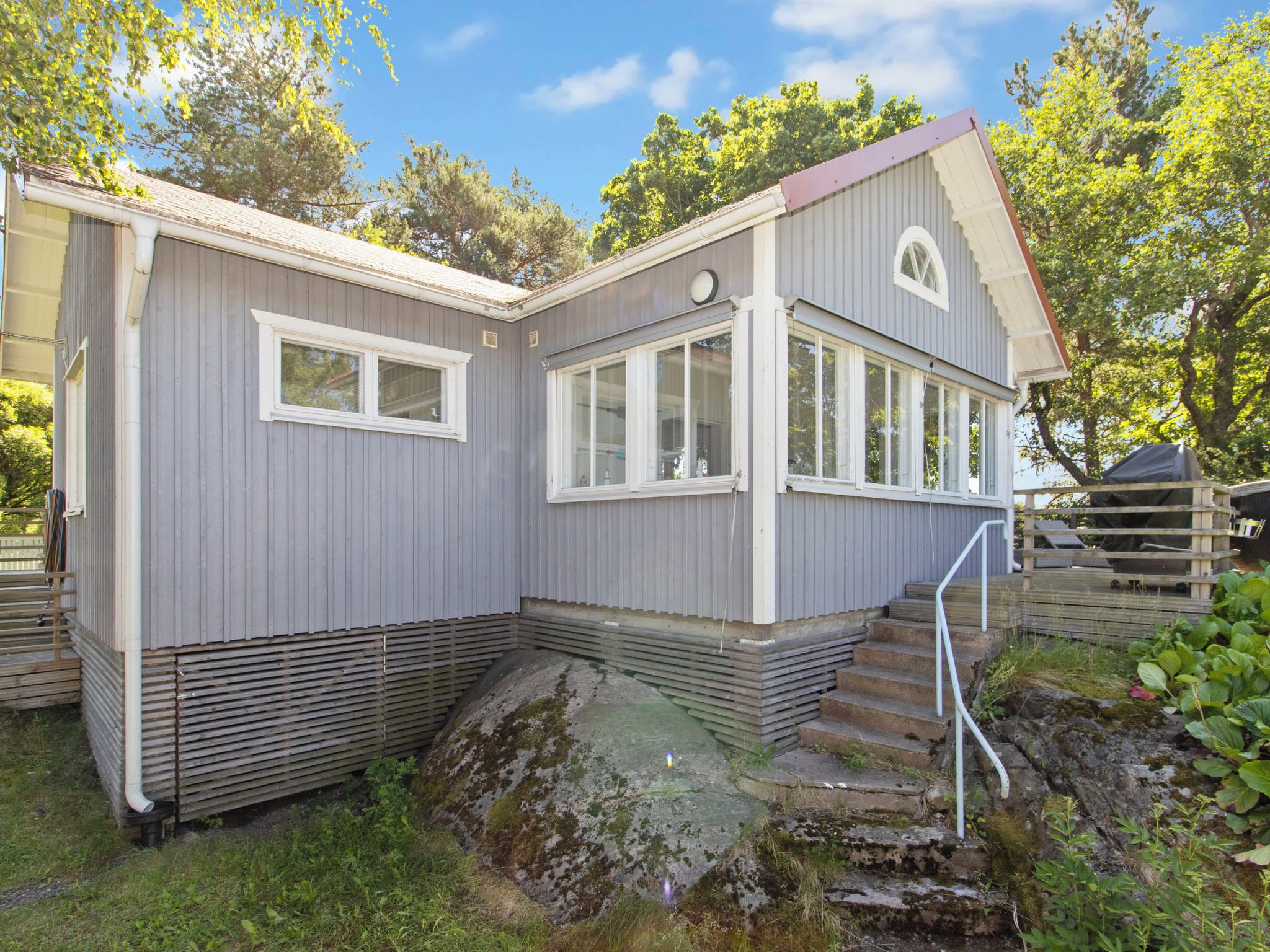 Ein zweistöckiges Haus mit einer kleinen Veranda und einer Treppe, die zum Eingang führt.