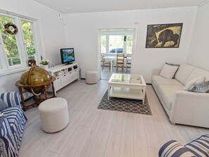 A modern living room with a television, a globe, a dining area, and a sofa.