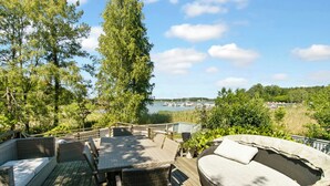 Eine Terrasse mit Korbmöbeln und Blick auf eine Marina.