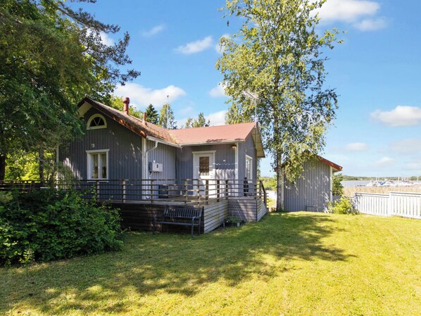 A two-story house with a porch, a small deck, and a view of a lake with boats. - Villa niemelä by Interhome (Naantali)