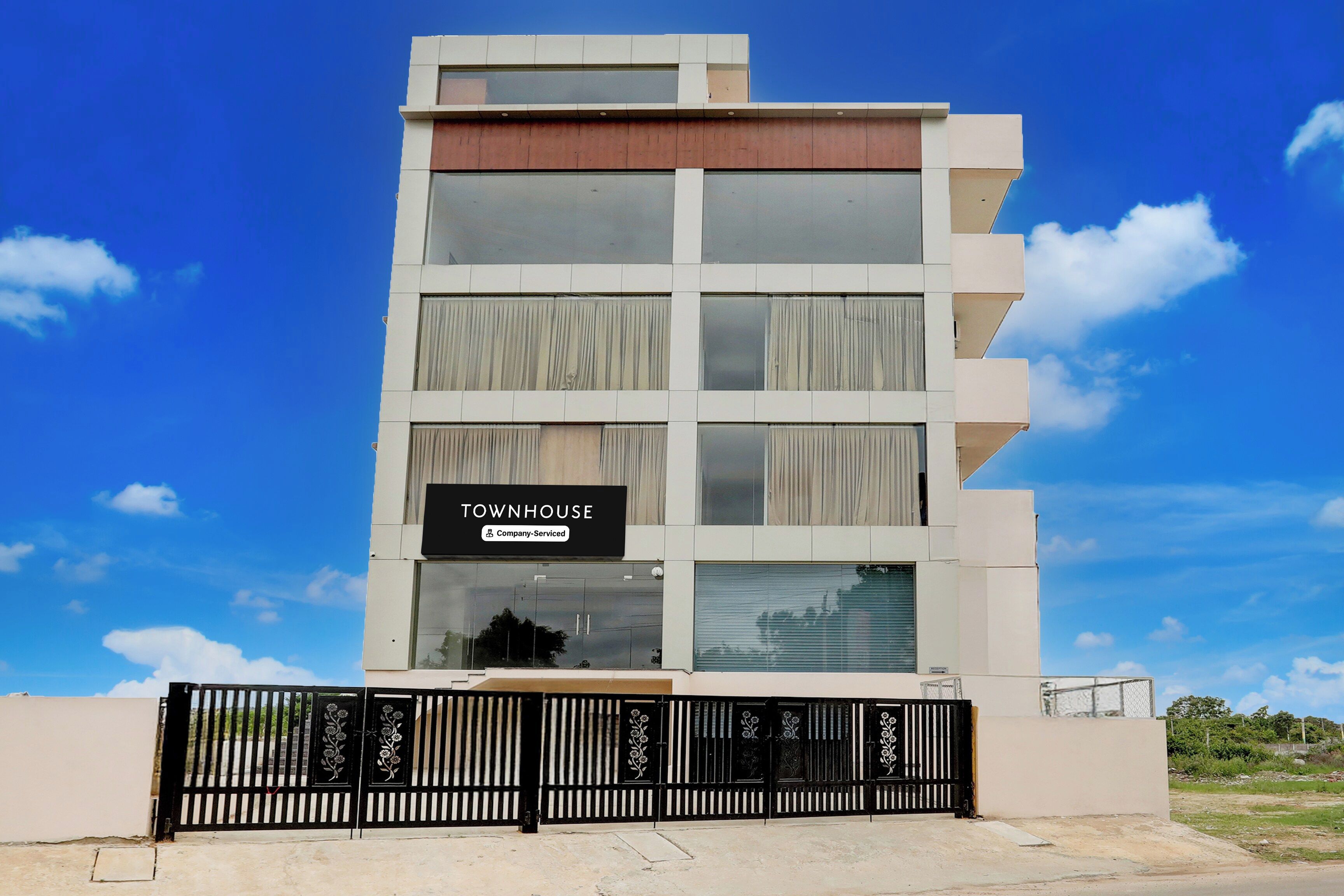 Un edificio de varios pisos con un letrero que dice 'TOWNHOUSE' y una entrada con portón.