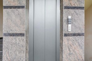 An elevator with a metallic interior and a control panel on the wall. - Townhouse Maralkunte Kateramma Temple (Bengaluru)