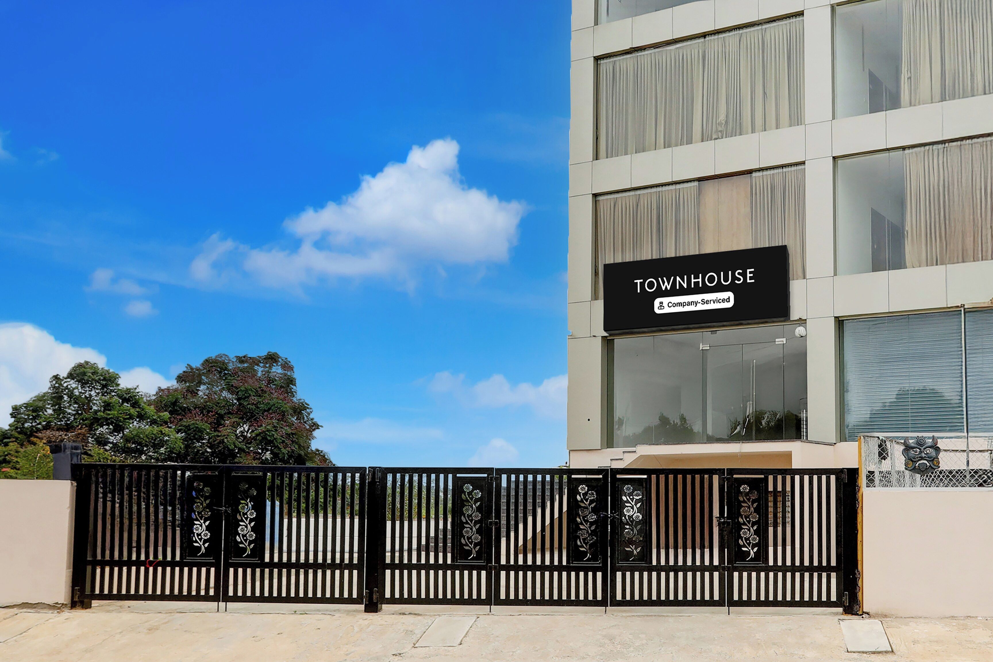Un bâtiment moderne avec une enseigne indiquant « IMMEUBLE D’HABITATION » et un symbole représentant l’entreprise qui en assure la gestion.