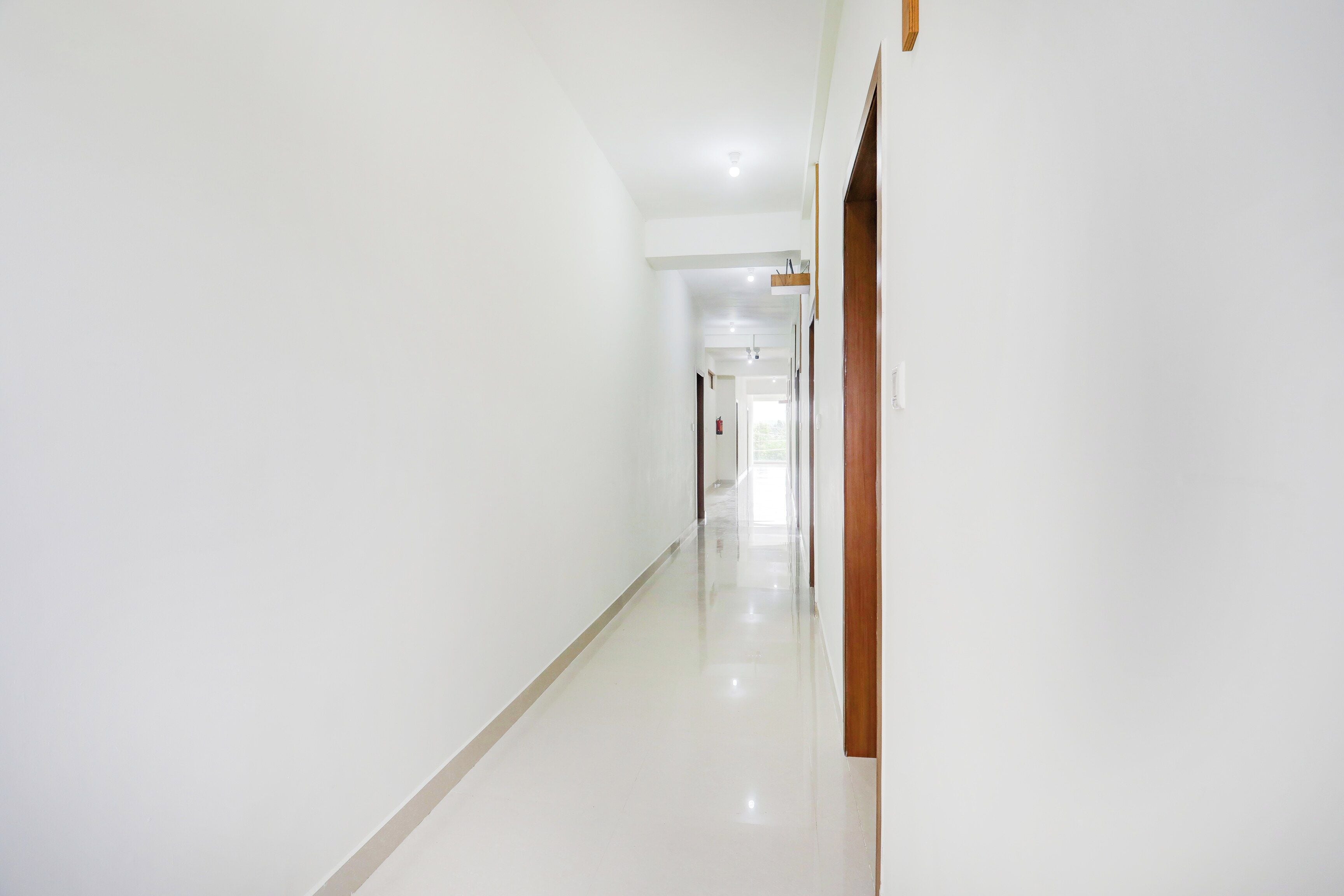 A clean, well-lit hallway with a wooden door on the right and a fire extinguisher mounted on the wall.