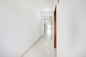 A clean, well-lit hallway with a wooden door on the right and a fire extinguisher mounted on the wall. - Townhouse Maralkunte Kateramma Temple (Bengaluru)