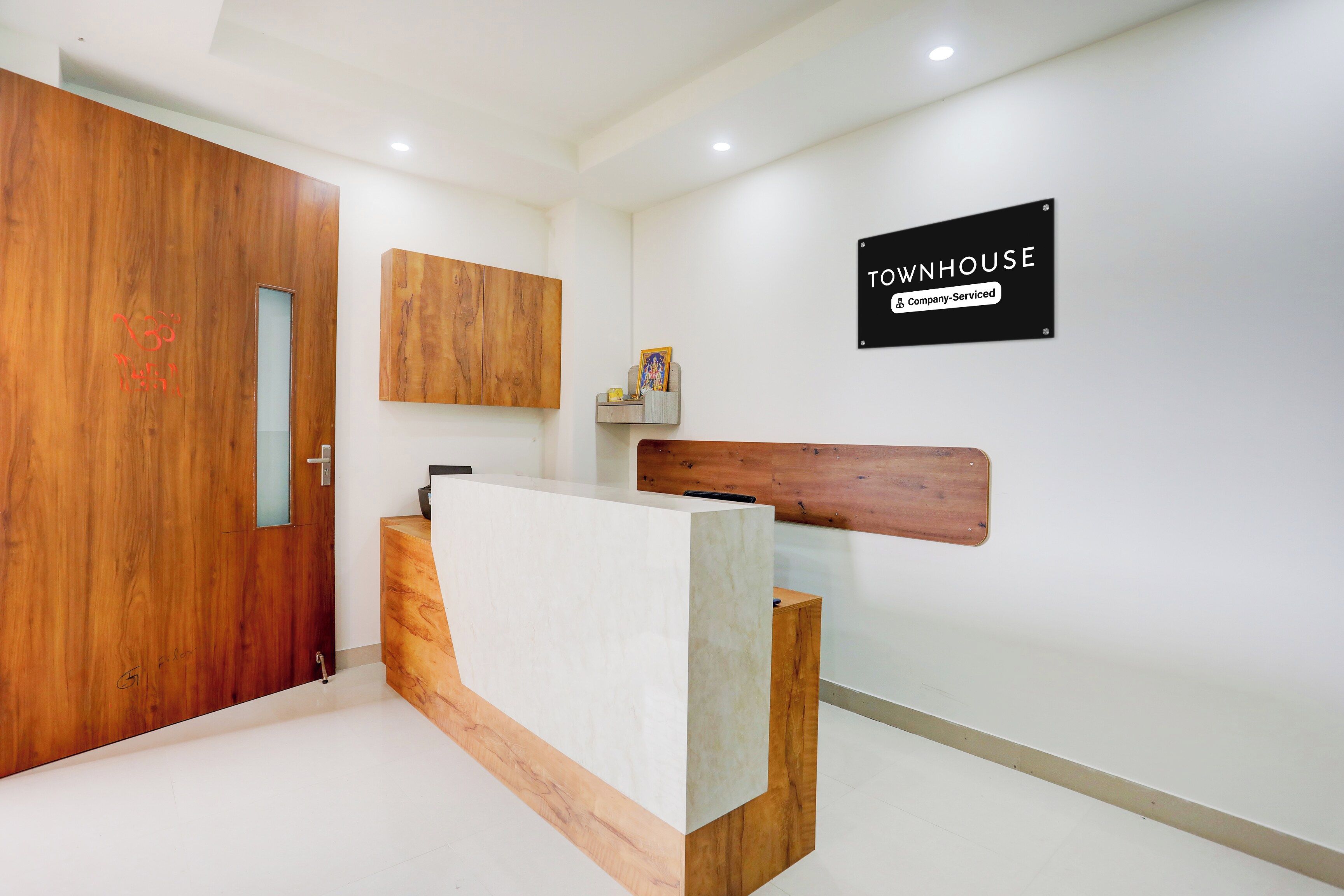 Un área de recepción con un mostrador de madera, un cartel que indica que es un almacén con servicios de empresa y una puerta grande de madera.