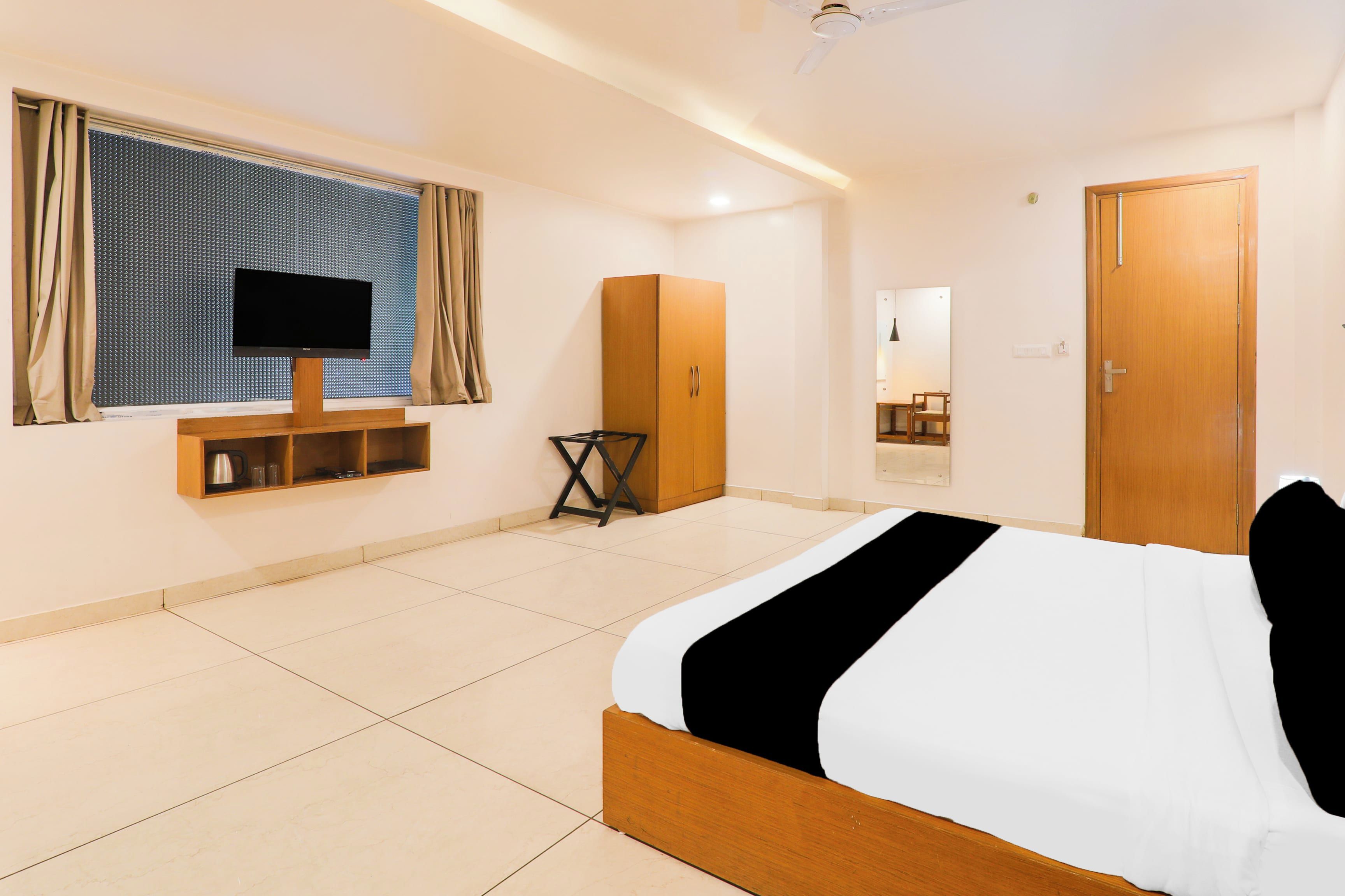 Una habitación de hotel con cama, televisión, armario y espejo.