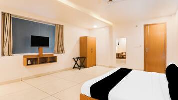Una habitación de hotel con cama, televisión, armario y espejo.