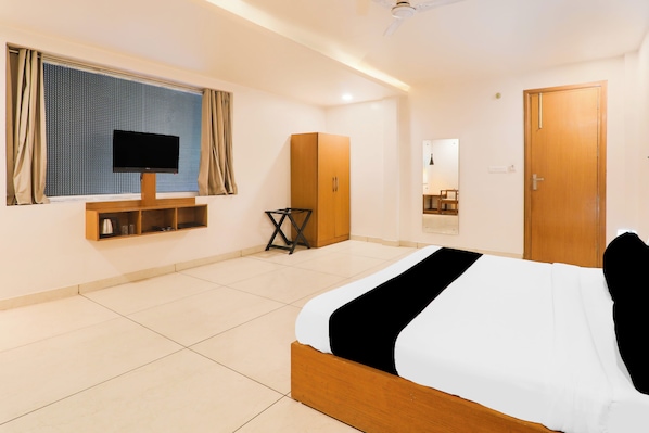 A hotel room with a bed, a television, a wardrobe, and a mirror.