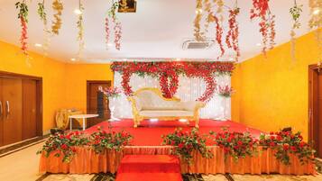 A stage with a golden sofa, red floral arrangements, and hanging decorations.