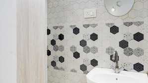 A bathroom with a white sink, a mirror, and a hexagonal patterned wall.