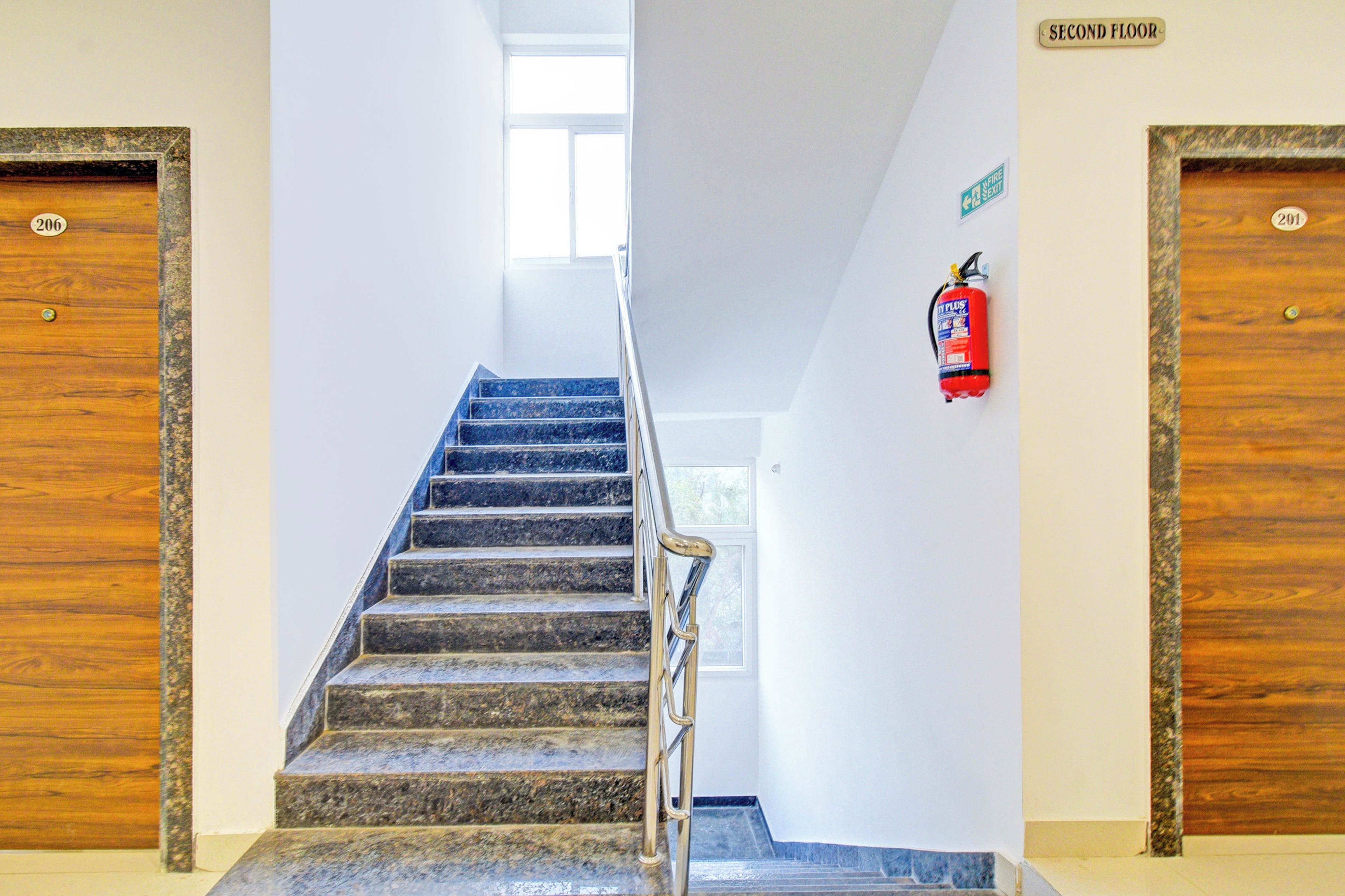 Una escalera con un extintor en la pared, que conduce a una puerta con la leyenda 'Segundo Piso'.