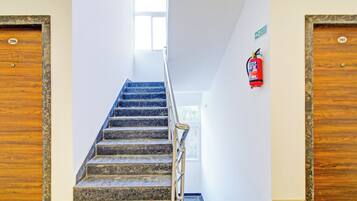 Una escalera con un extintor en la pared, que conduce a una puerta con la leyenda 'Segundo Piso'.