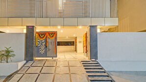 L’entrée d’un hôtel, avec un chemin dallé menant à un escalier et une porte décorative.