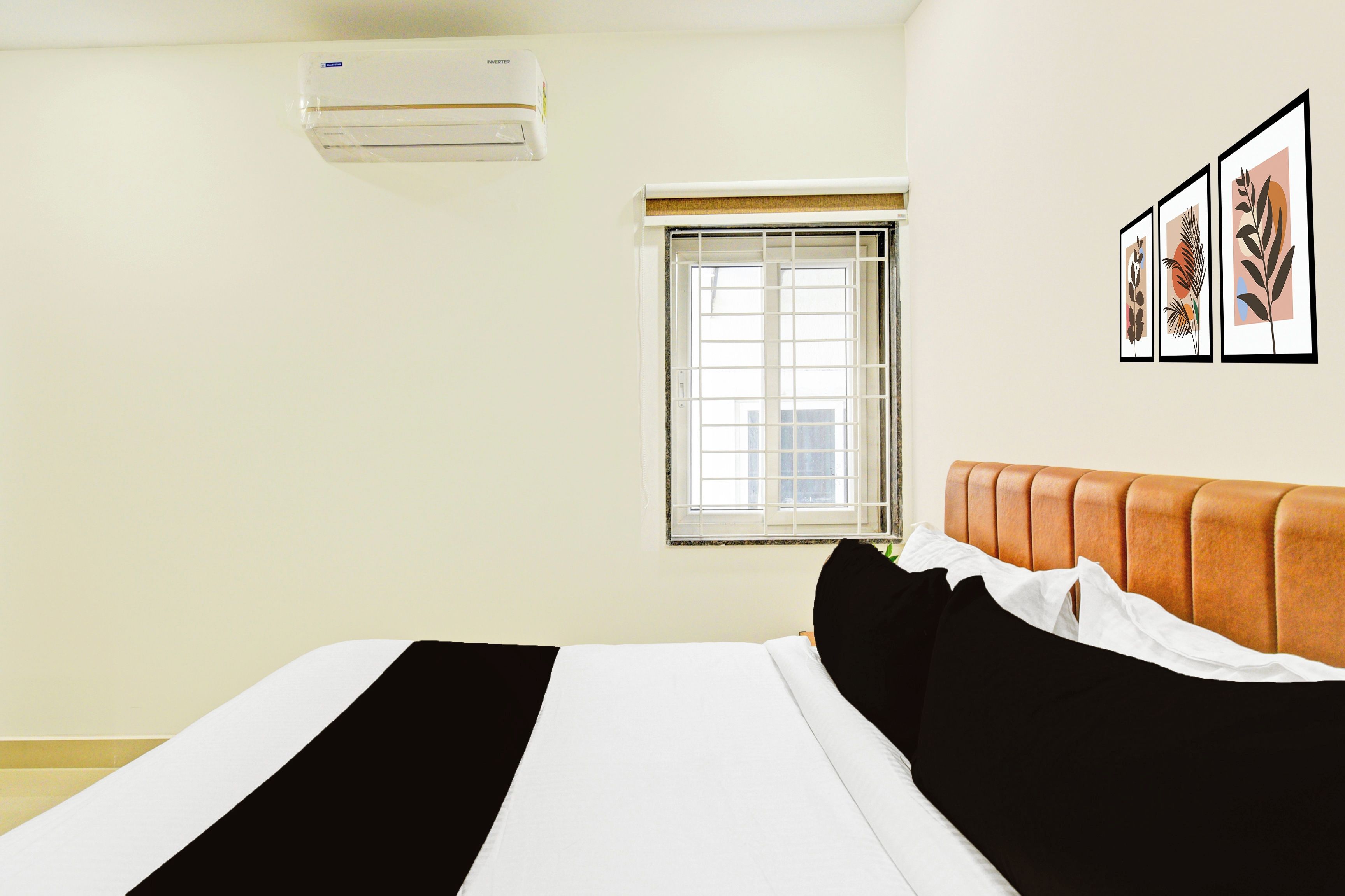 Una habitación de hotel con una cama, una ventana, aire acondicionado y decoración en la pared.