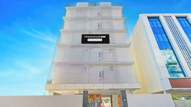 A modern building with a sign reading 'TOWNHOUSE OAK' and a company-serviced label.