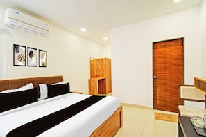 Una habitación de hotel con cama, armario de madera, una mesita con bandeja y una puerta.