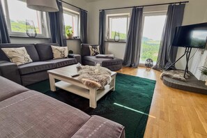 A modern living room with a grey sofa, a coffee table, and a television. - Dreamy Roof Terrace Eifelgluck (Pelm)